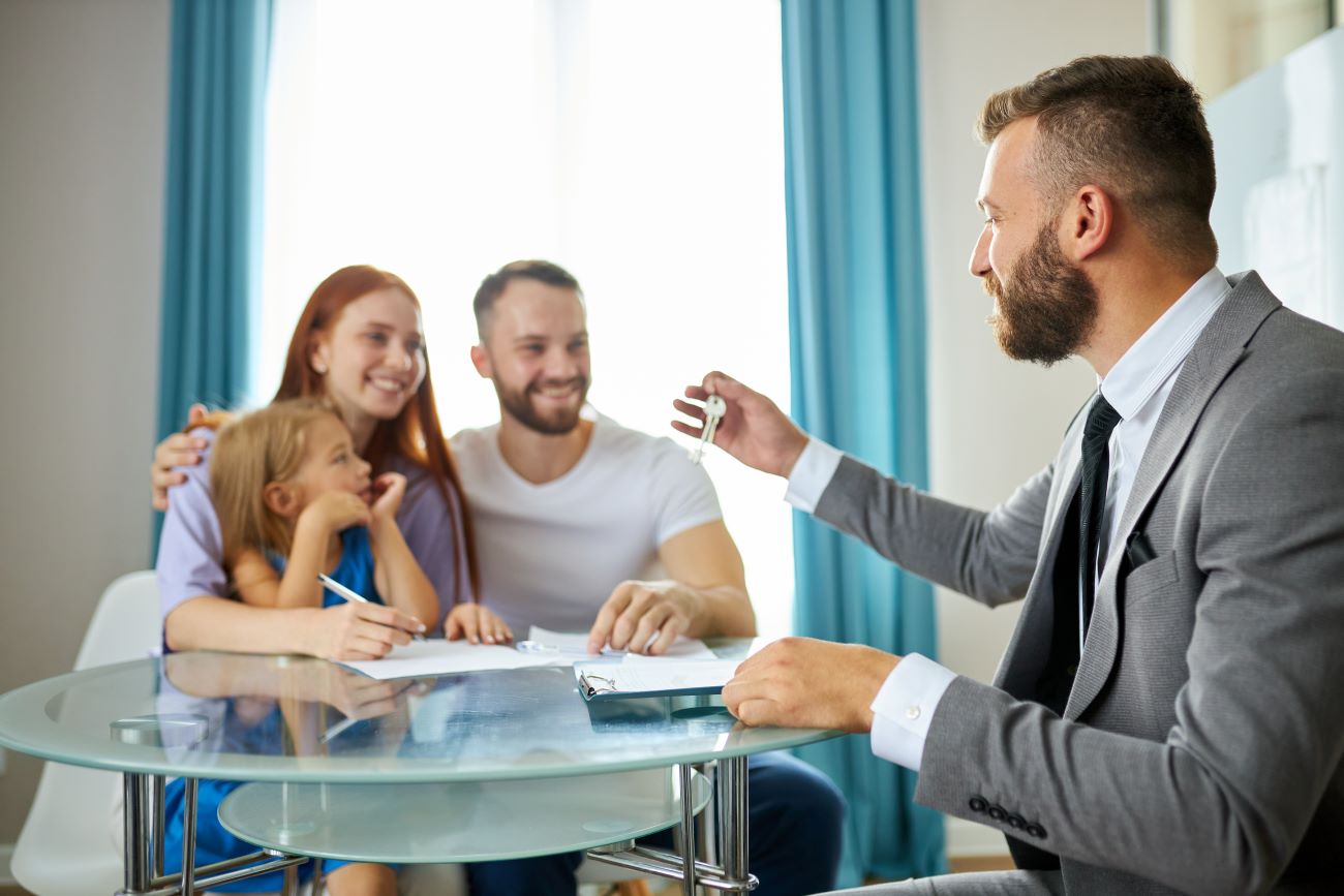 young caucasian family getting keys from their house by real estate agent, male in suit give them keys, happy family with child girl sit smiling